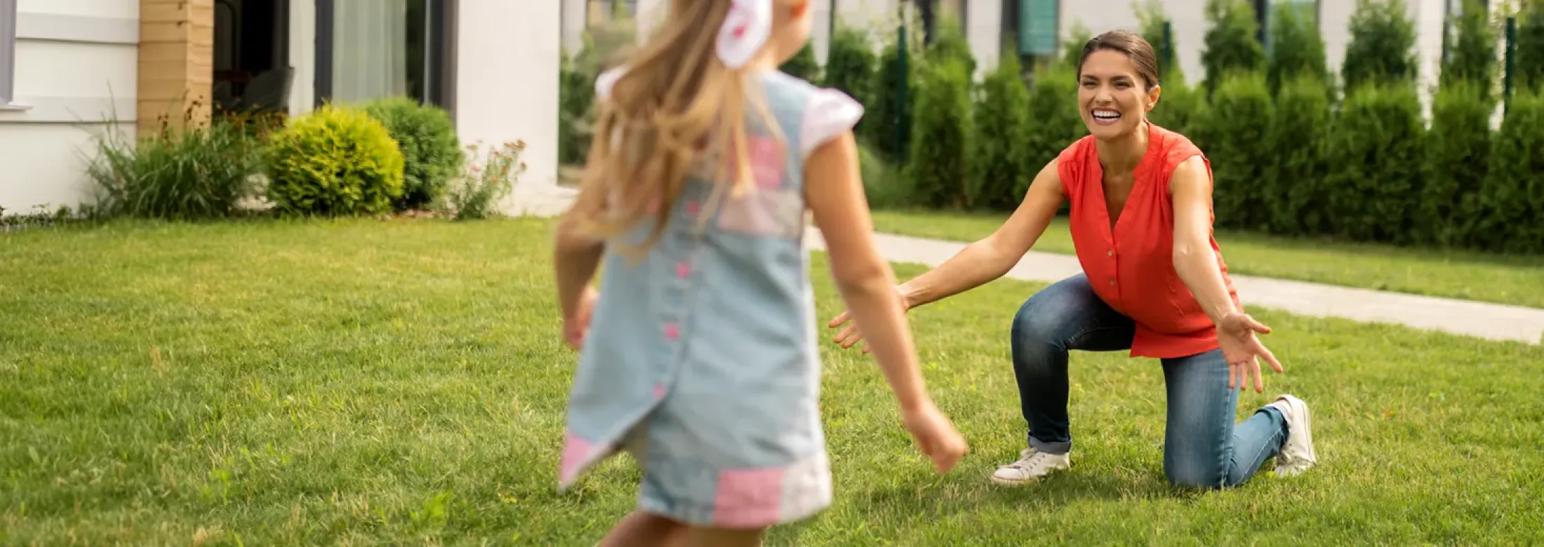 Mother and daughter playing outside on green healthy lawn